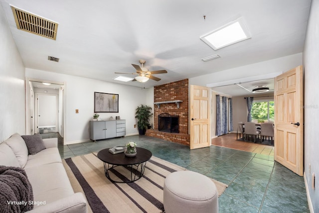 living area featuring dark tile patterned floors, visible vents, a brick fireplace, and a ceiling fan