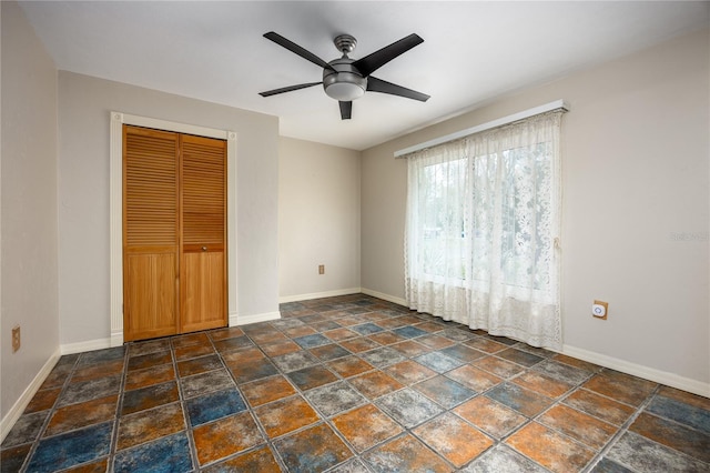 unfurnished bedroom with a ceiling fan, baseboards, and a closet