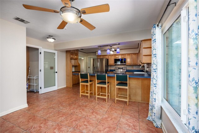 kitchen featuring visible vents, a sink, tasteful backsplash, dark countertops, and stainless steel appliances