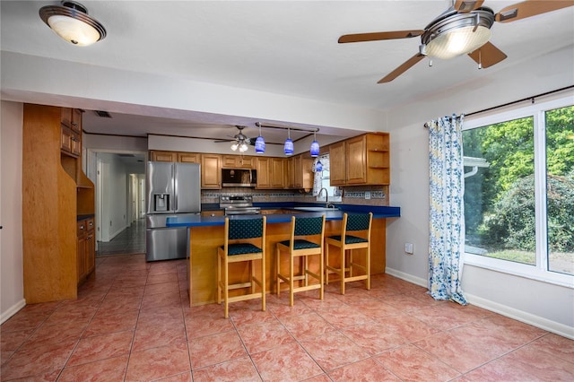 kitchen with open shelves, stainless steel appliances, dark countertops, and a wealth of natural light