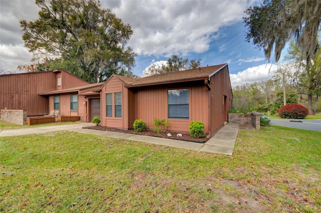 view of front of property with an attached garage, a front lawn, and concrete driveway