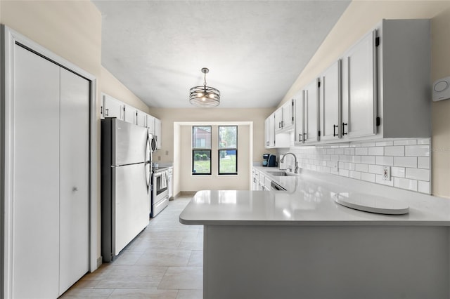 kitchen with stainless steel appliances, light countertops, backsplash, vaulted ceiling, and a peninsula