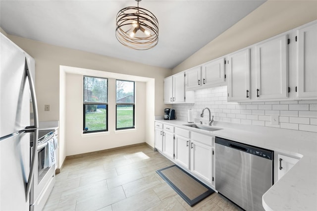 kitchen featuring white cabinets, backsplash, freestanding refrigerator, stainless steel dishwasher, and a sink