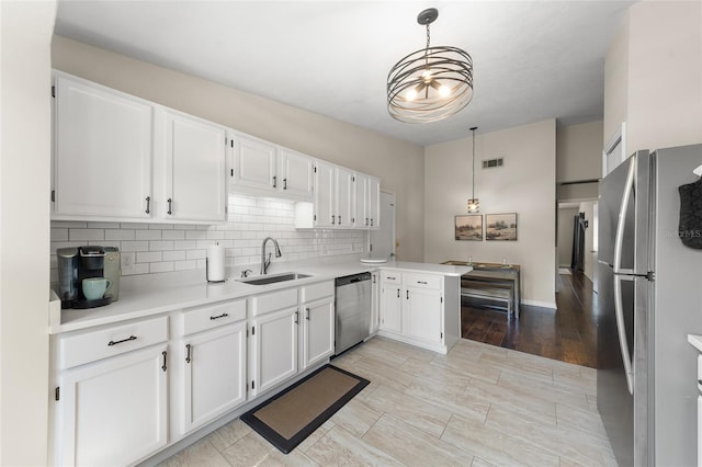 kitchen with a sink, visible vents, white cabinets, light countertops, and appliances with stainless steel finishes