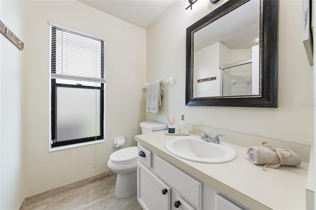 bathroom with toilet, walk in shower, wood finished floors, and vanity