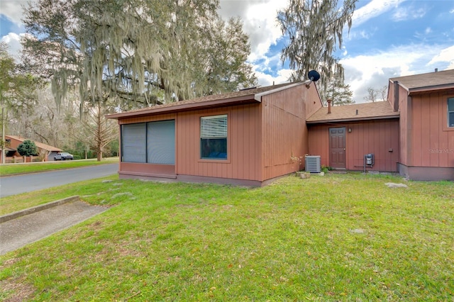 rear view of property with a yard and central air condition unit