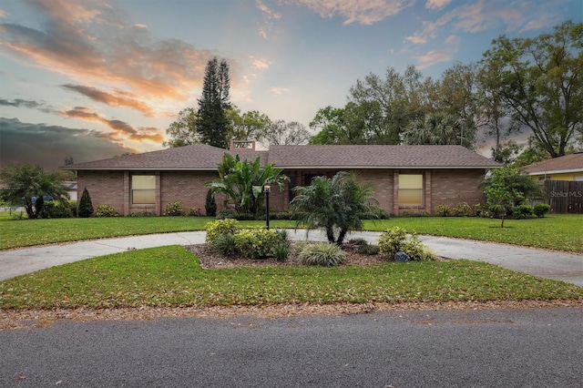 view of front of property with concrete driveway, a front lawn, and brick siding