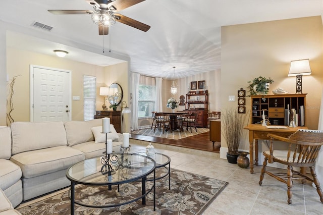 living room featuring light tile patterned floors, ceiling fan, and visible vents