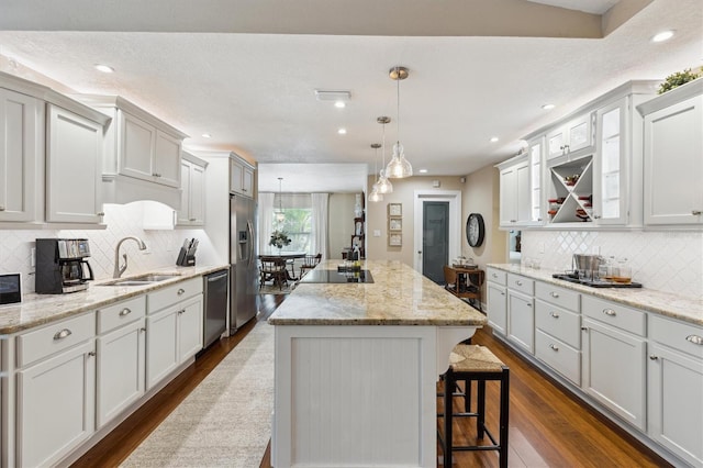 kitchen featuring a center island, dark wood-style flooring, hanging light fixtures, appliances with stainless steel finishes, and a sink