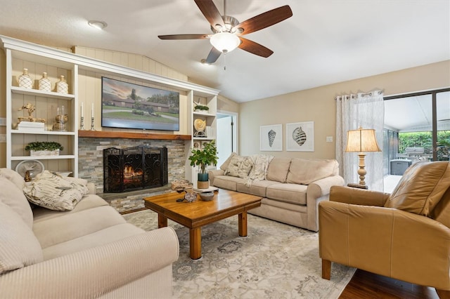 living room with lofted ceiling, a fireplace, wood finished floors, and a ceiling fan