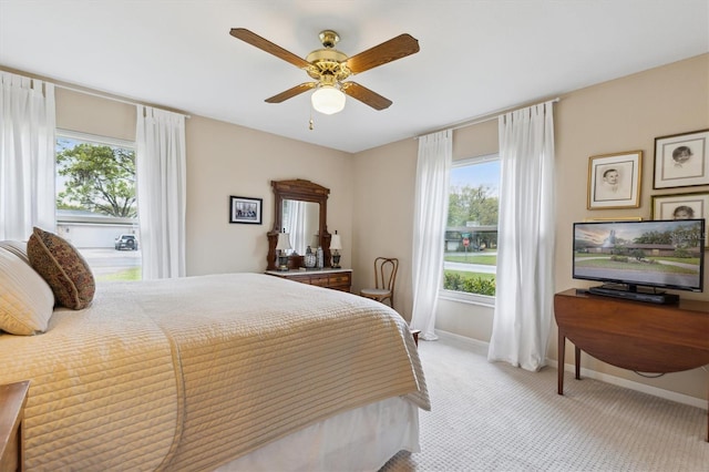 carpeted bedroom featuring ceiling fan, multiple windows, and baseboards