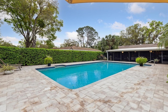 view of swimming pool featuring a patio, a sunroom, and a fenced in pool