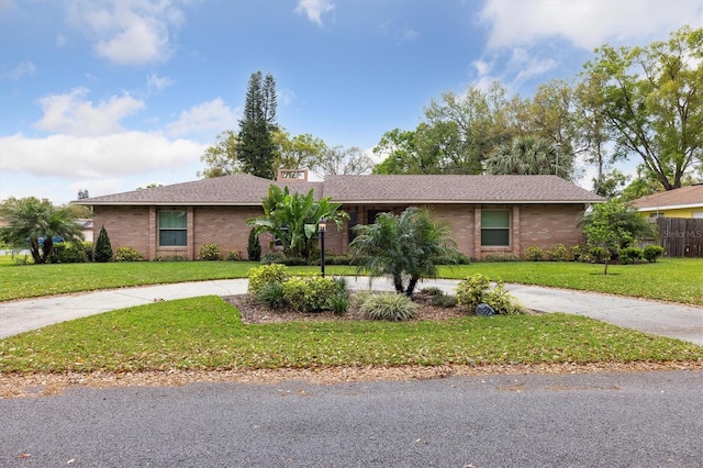 single story home featuring concrete driveway, brick siding, and a front yard