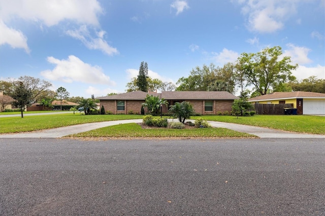 ranch-style house featuring curved driveway, a front lawn, and fence