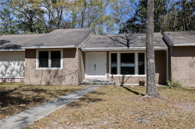 ranch-style home featuring a front lawn and roof with shingles