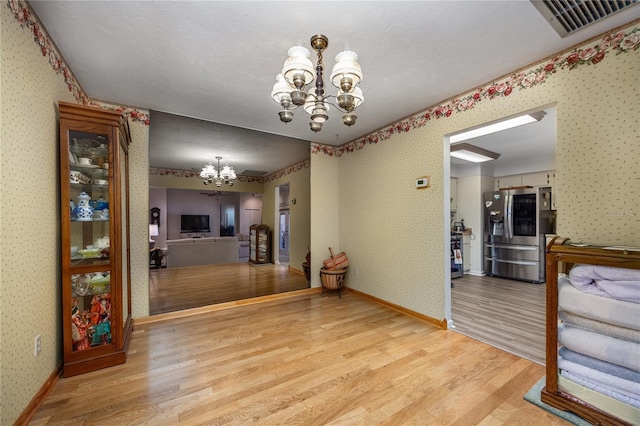 dining area with a chandelier, light wood-type flooring, baseboards, and wallpapered walls