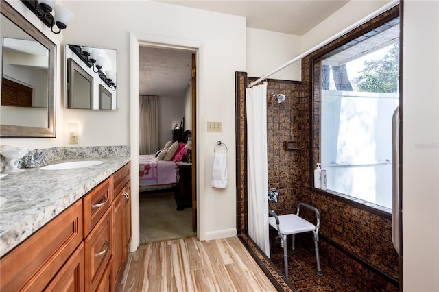 ensuite bathroom featuring a healthy amount of sunlight, vanity, a shower with shower curtain, and wood finished floors