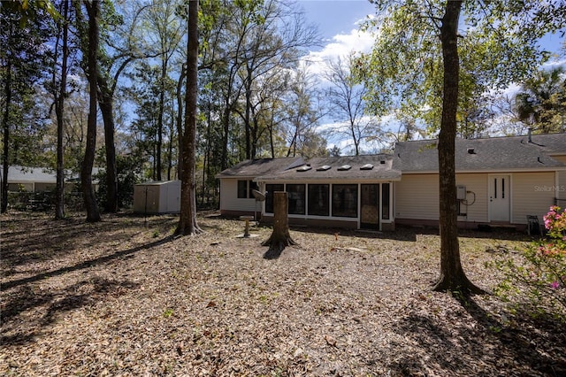 rear view of property featuring a sunroom, an outdoor structure, and a storage unit