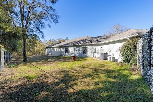 rear view of house with a yard, cooling unit, and stucco siding