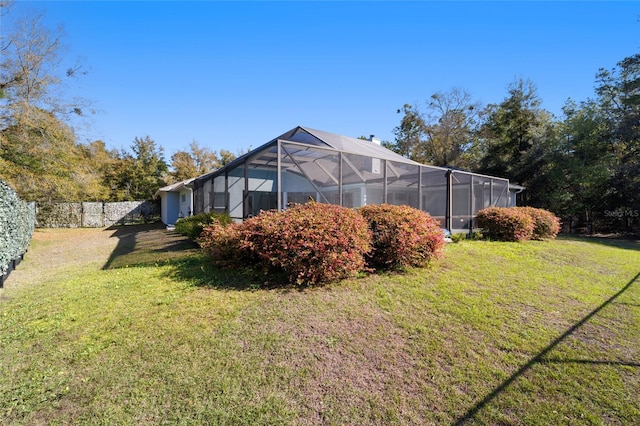 rear view of property featuring a lanai, a chimney, fence, and a lawn