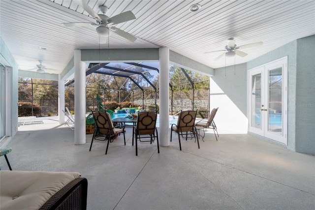 view of patio with a lanai, ceiling fan, outdoor dining area, and french doors