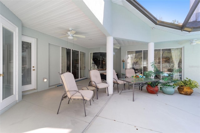 view of patio with ceiling fan and glass enclosure