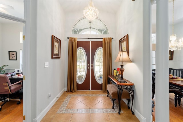 entrance foyer featuring a chandelier, light tile patterned floors, and baseboards