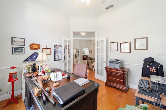 home office with light wood finished floors, baseboards, visible vents, ceiling fan, and french doors