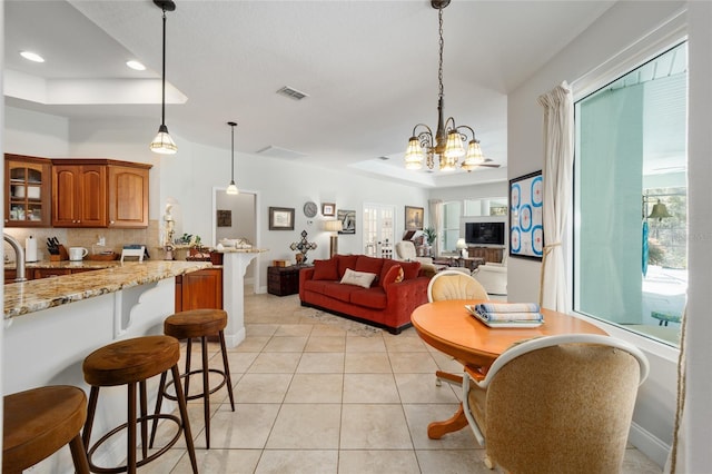 interior space featuring a tray ceiling, visible vents, baseboards, and light tile patterned floors