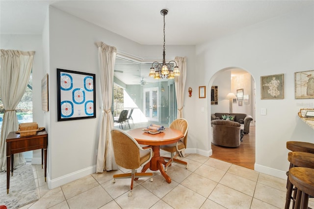 dining room with a healthy amount of sunlight, light tile patterned floors, baseboards, and arched walkways