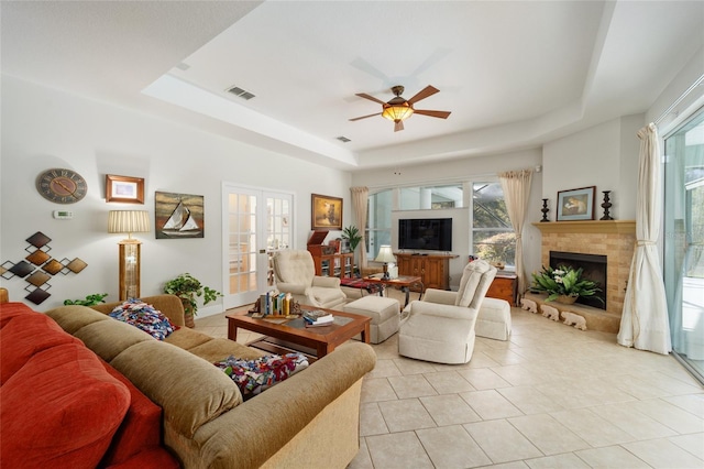 living room featuring french doors, a fireplace, a raised ceiling, and visible vents