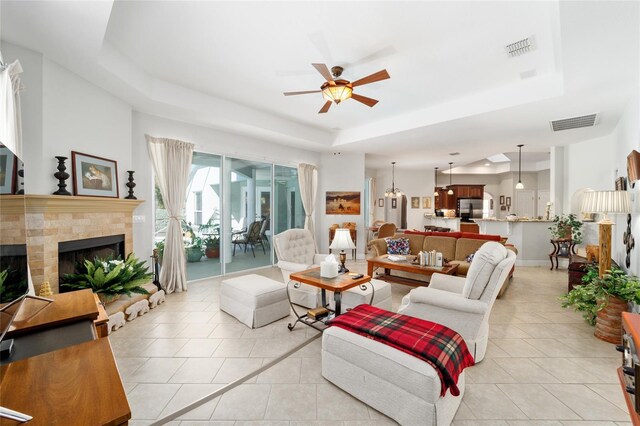 living room featuring a fireplace, visible vents, a raised ceiling, and light tile patterned flooring