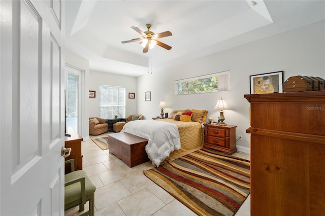 bedroom with light tile patterned floors, multiple windows, access to exterior, and a raised ceiling