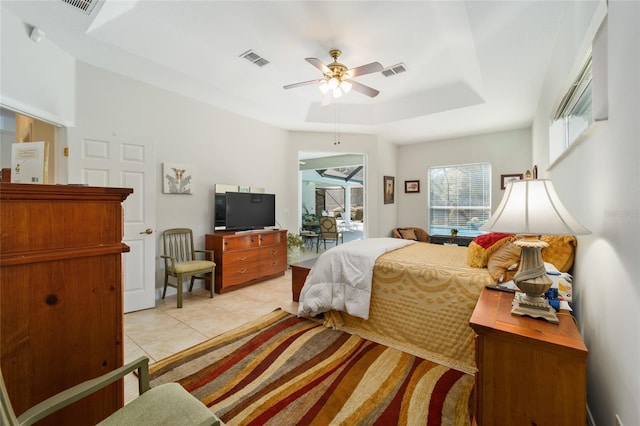 bedroom with light tile patterned flooring, a raised ceiling, visible vents, and access to exterior