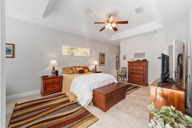 bedroom with a tray ceiling, visible vents, and baseboards