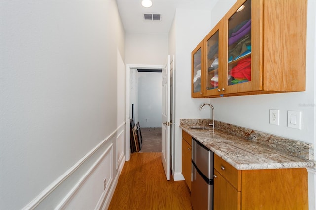 hall with light wood-type flooring, a sink, and visible vents