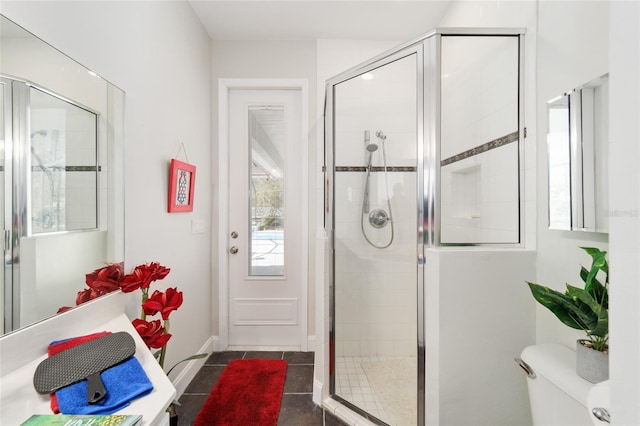 bathroom featuring toilet, a stall shower, tile patterned flooring, and baseboards