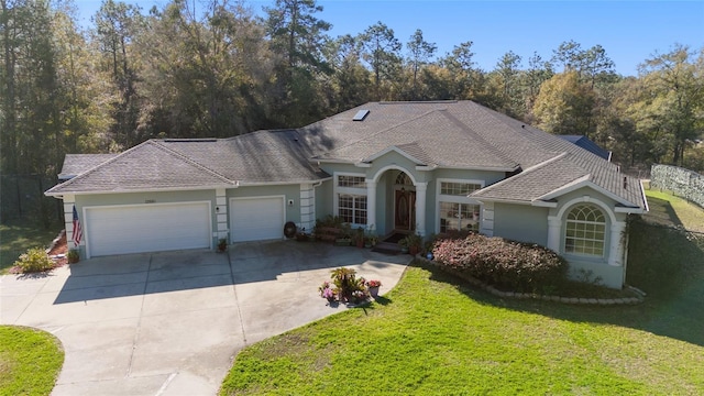 view of front of property with a garage, driveway, a shingled roof, a front lawn, and stucco siding