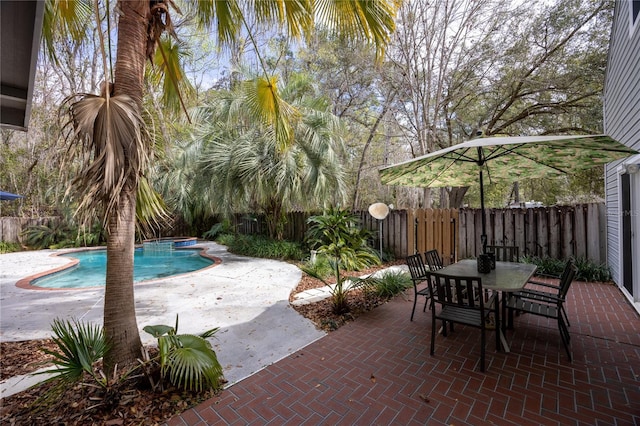 view of patio / terrace featuring a fenced backyard, a jacuzzi, a fenced in pool, and outdoor dining space