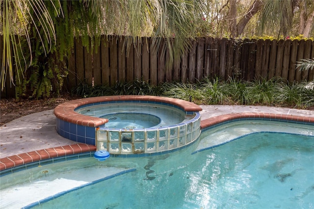 view of swimming pool with a pool with connected hot tub and fence