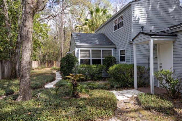 exterior space featuring a shingled roof and fence