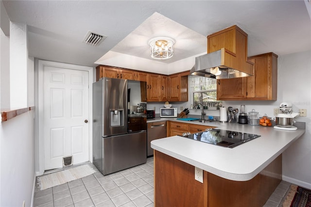 kitchen with a peninsula, visible vents, appliances with stainless steel finishes, ventilation hood, and brown cabinetry