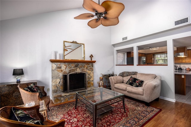 living room with visible vents, wood finished floors, and a stone fireplace