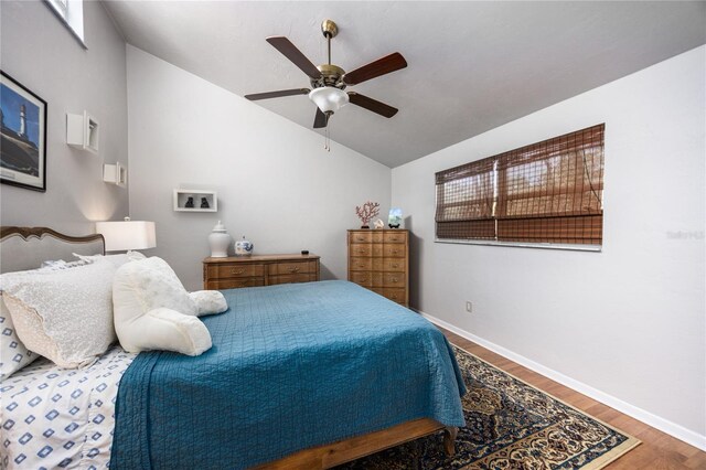 bedroom with lofted ceiling, ceiling fan, baseboards, and wood finished floors