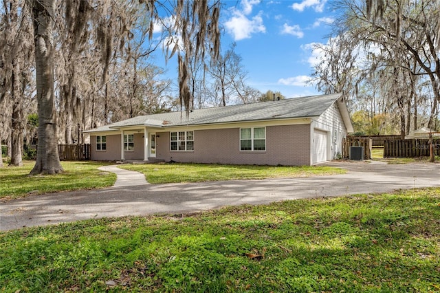 ranch-style home with brick siding, an attached garage, fence, driveway, and a front lawn