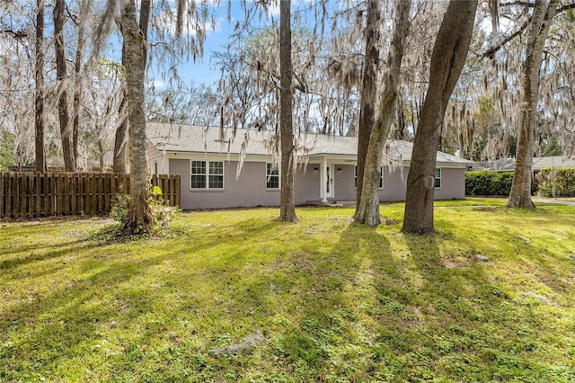 rear view of house featuring fence, a lawn, and brick siding