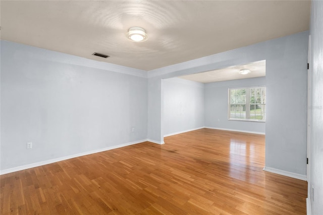 unfurnished room featuring light wood-style floors, visible vents, and baseboards