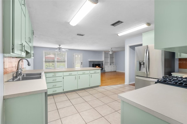 kitchen featuring light tile patterned floors, visible vents, green cabinetry, and a sink