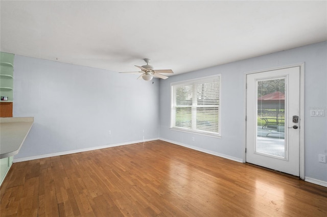 unfurnished living room featuring hardwood / wood-style flooring, plenty of natural light, baseboards, and ceiling fan