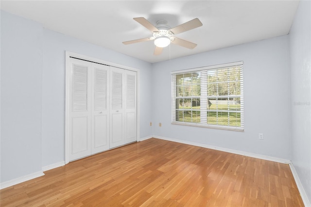 unfurnished bedroom featuring a closet, light wood-type flooring, a ceiling fan, and baseboards